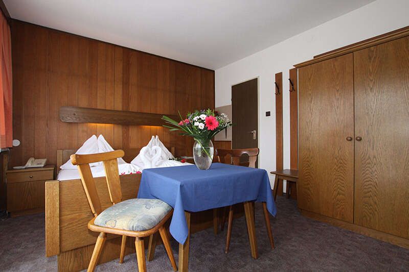 Doppelbettzimmer mit Holzverkleidung und Tisch mit Stühlen